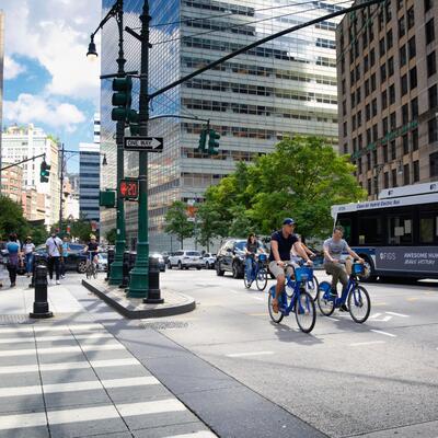 Bikers navigate a city street next to a bus