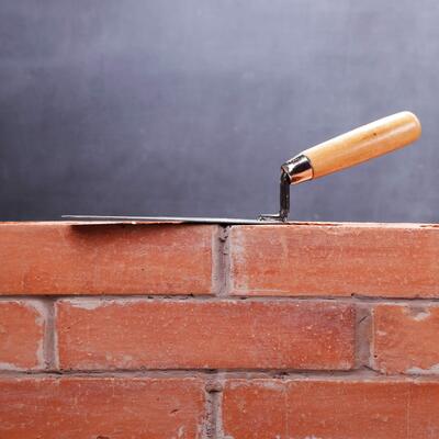 A trowel atop a brick wall under construction