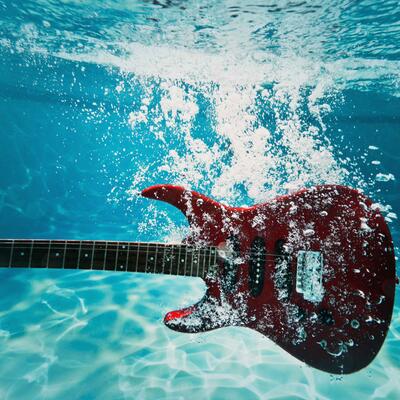 An electric guitar sinking in a pool