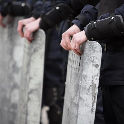 Riot police stand opposite a protest